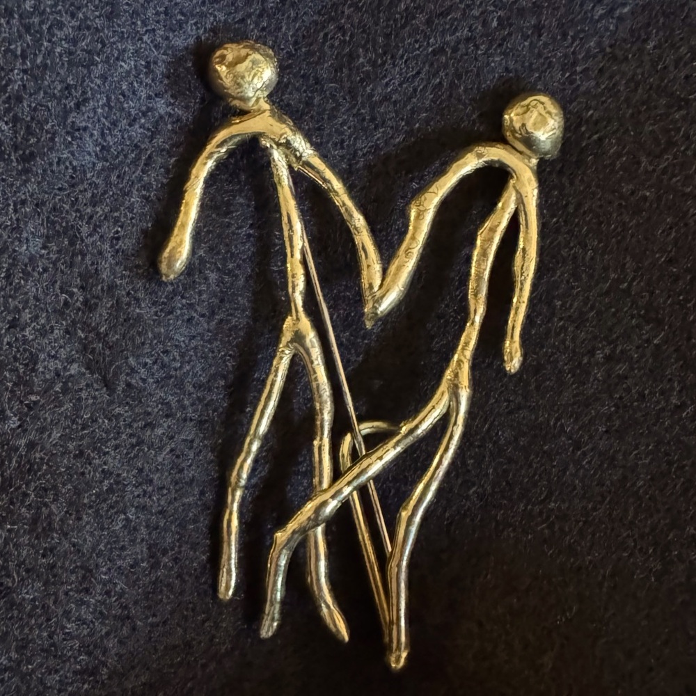Soldered metal brooch. Gold color of figures holding hands